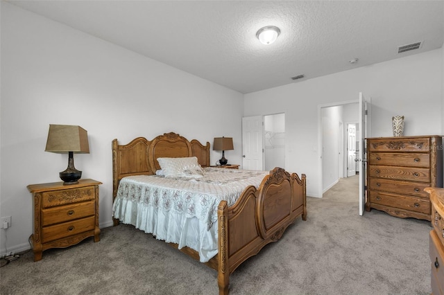 bedroom featuring a walk in closet, a closet, carpet, and a textured ceiling