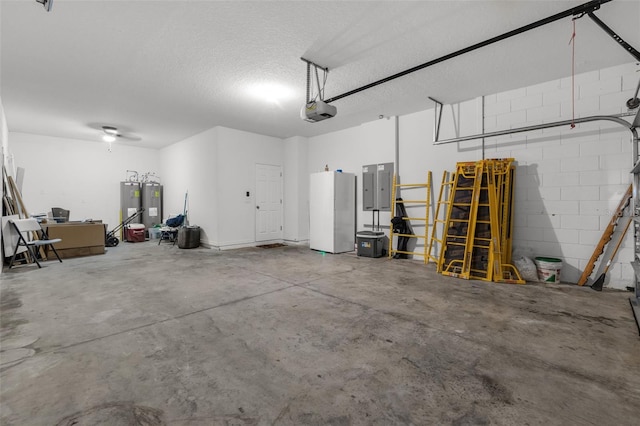 garage with electric panel, white fridge, a garage door opener, and water heater