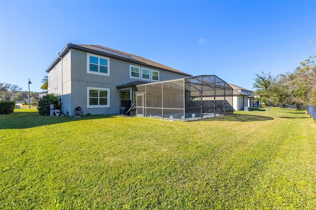 rear view of house featuring a lanai, a lawn, and a swimming pool