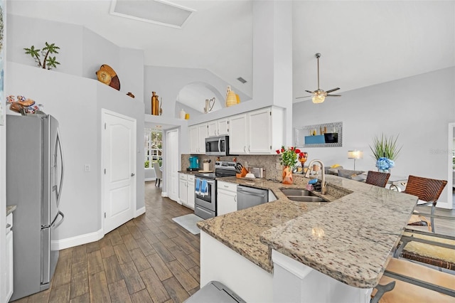 kitchen with appliances with stainless steel finishes, white cabinetry, sink, a kitchen breakfast bar, and kitchen peninsula