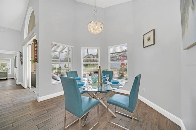 dining space with a high ceiling, wood-type flooring, and an inviting chandelier