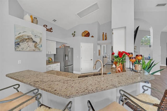 kitchen with stainless steel refrigerator with ice dispenser, white cabinetry, kitchen peninsula, and sink