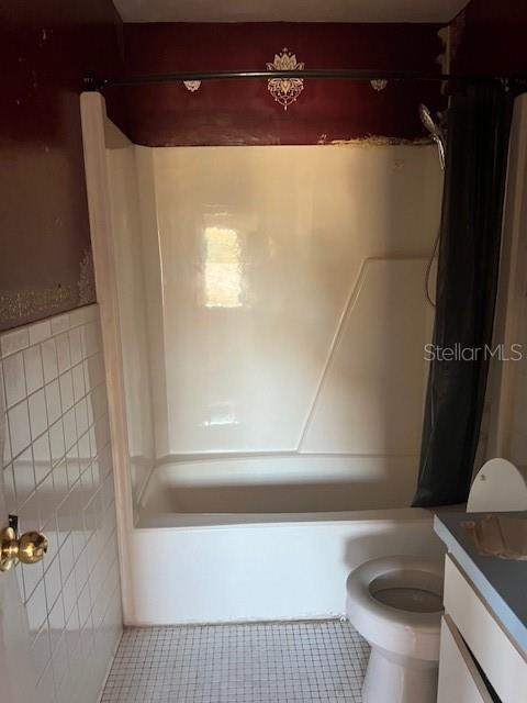 full bathroom featuring tile patterned flooring, toilet, tile walls, and shower / bath combo with shower curtain