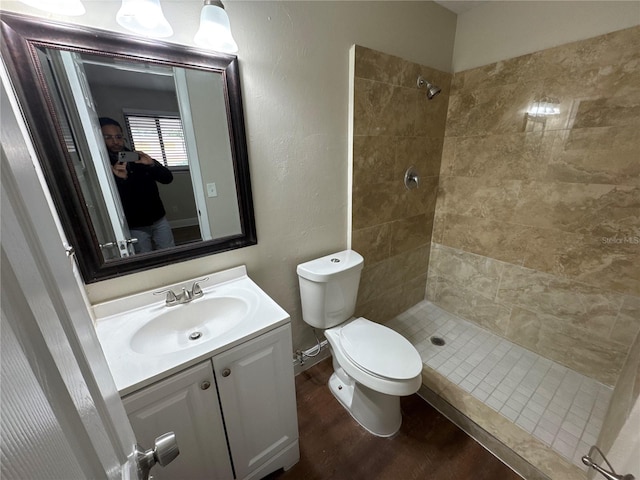 bathroom with tiled shower, vanity, wood-type flooring, and toilet