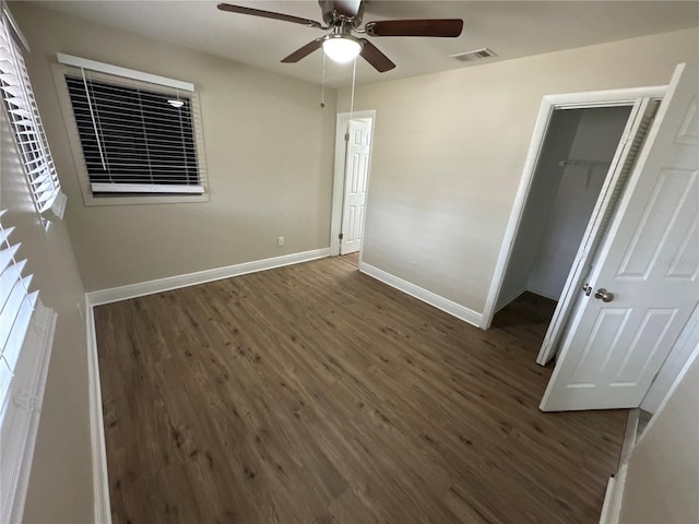 unfurnished bedroom featuring a walk in closet, ceiling fan, a closet, and dark hardwood / wood-style floors