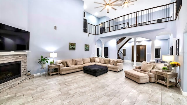 living room featuring ceiling fan, a fireplace, and decorative columns