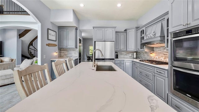 kitchen featuring sink, gray cabinets, stainless steel appliances, light stone countertops, and backsplash