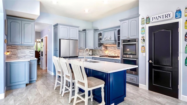 kitchen featuring an island with sink, sink, a breakfast bar area, custom exhaust hood, and stainless steel appliances