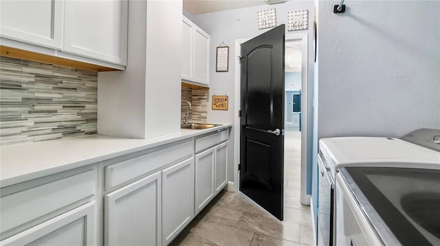 kitchen featuring tasteful backsplash, sink, washer and dryer, and white cabinets