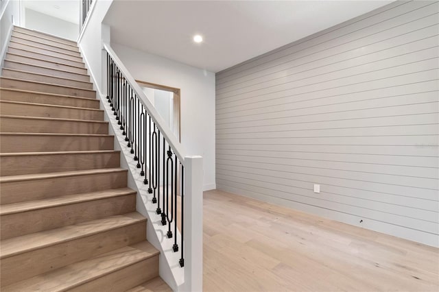 stairs with hardwood / wood-style floors and wood walls