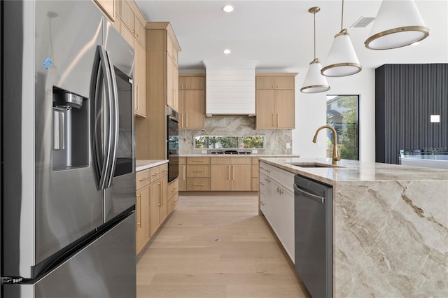 kitchen with decorative light fixtures, light brown cabinetry, sink, and stainless steel appliances