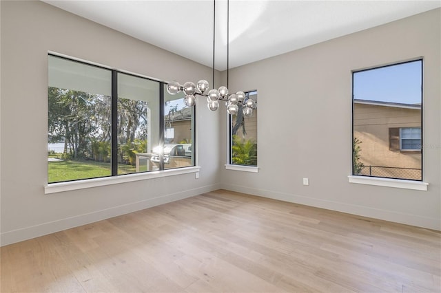 unfurnished dining area featuring a notable chandelier and light hardwood / wood-style floors