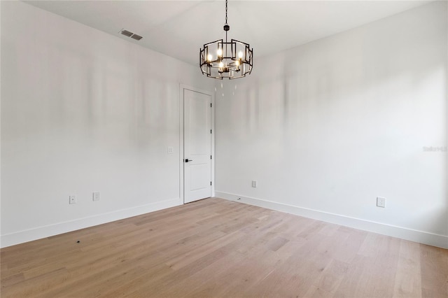 unfurnished room featuring light hardwood / wood-style flooring and a notable chandelier