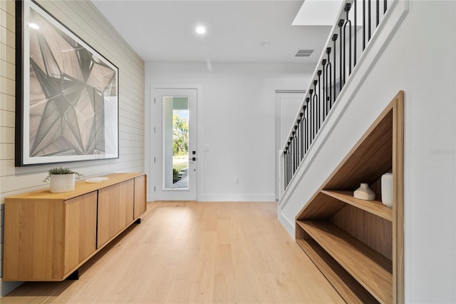 entrance foyer with light hardwood / wood-style floors and wood walls