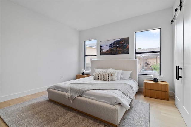 bedroom with light hardwood / wood-style flooring and a barn door