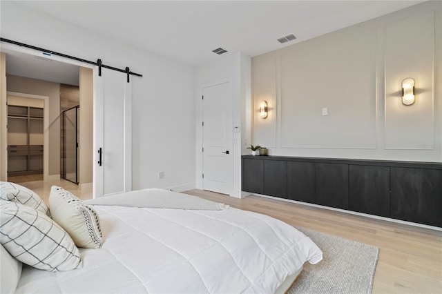 bedroom featuring hardwood / wood-style flooring, a barn door, and a spacious closet