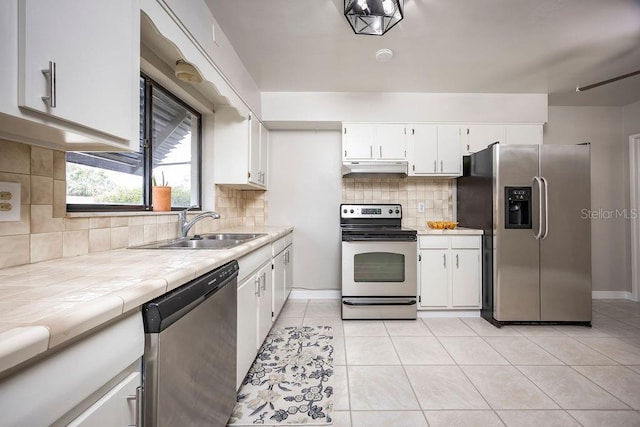 kitchen with tasteful backsplash, white cabinets, stainless steel appliances, and light tile patterned floors