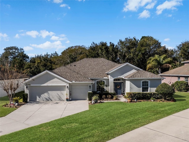 ranch-style home with a garage, a shingled roof, concrete driveway, a front lawn, and stucco siding