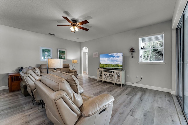 living room featuring ceiling fan, a textured ceiling, and light wood-type flooring