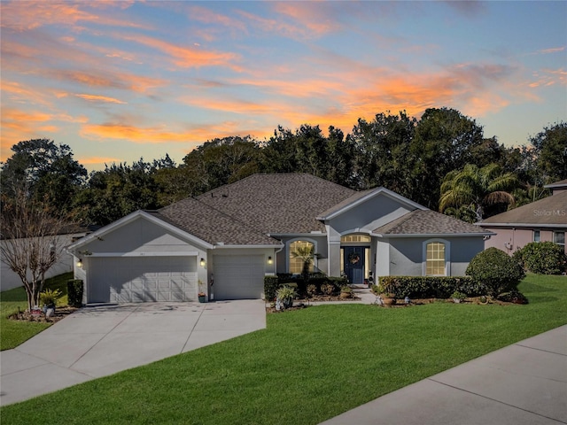 ranch-style home with a garage, driveway, a front lawn, and stucco siding