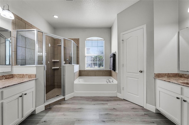 bathroom featuring a textured ceiling, wood finished floors, vanity, and a shower stall