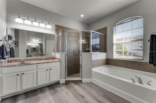 full bath with a stall shower, a garden tub, and wood finished floors