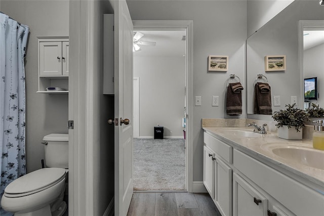 full bathroom featuring double vanity, a sink, toilet, and wood finished floors