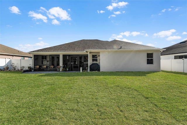 rear view of property featuring a sunroom, a fenced backyard, a lawn, and stucco siding