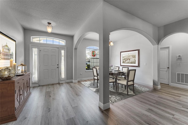 entryway with visible vents, a textured ceiling, baseboards, and wood finished floors