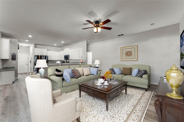 living area with recessed lighting, visible vents, light wood-style floors, ceiling fan, and baseboards