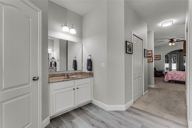 bathroom featuring connected bathroom, wood finished floors, a ceiling fan, vanity, and baseboards