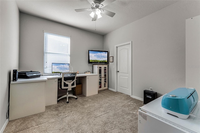 office space with light colored carpet, ceiling fan, a textured ceiling, and baseboards