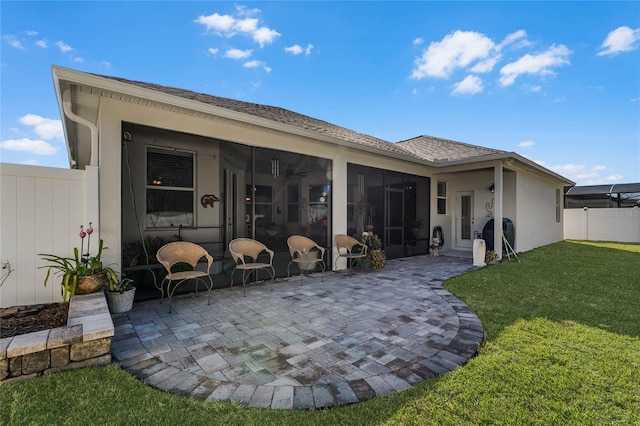 back of property featuring a patio, a sunroom, fence, a yard, and stucco siding