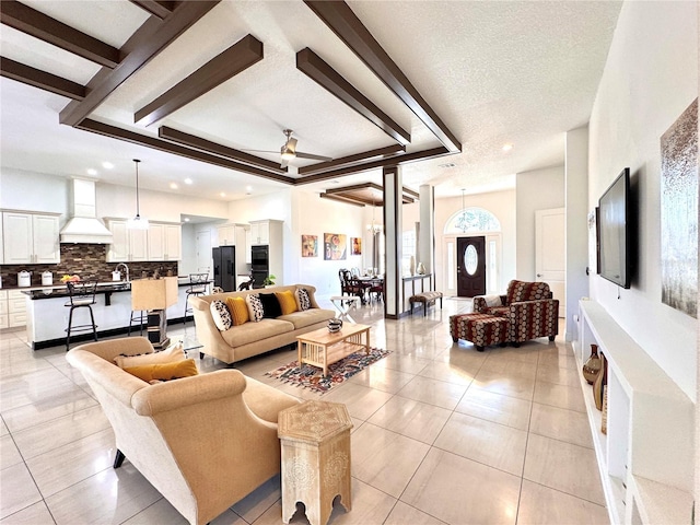 living room with sink, ceiling fan, light tile patterned floors, and a textured ceiling