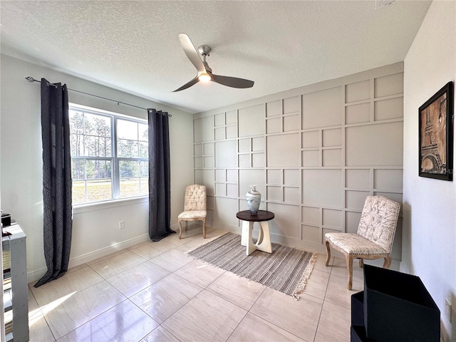 living area featuring ceiling fan, a textured ceiling, and light tile patterned floors