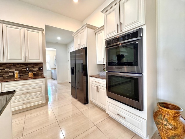 kitchen with dark stone countertops, double oven, tasteful backsplash, and black fridge with ice dispenser