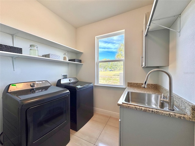 clothes washing area with sink, light tile patterned flooring, and washer and dryer