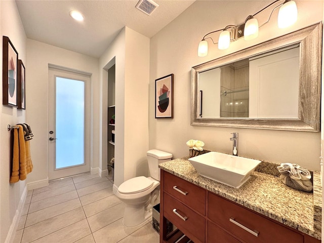 bathroom with tile patterned flooring, a textured ceiling, toilet, walk in shower, and vanity