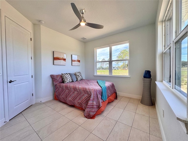 tiled bedroom with ceiling fan and a textured ceiling