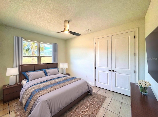 tiled bedroom with ceiling fan, a textured ceiling, and a closet