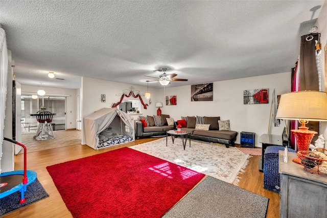 living room featuring ceiling fan, light hardwood / wood-style floors, and a textured ceiling