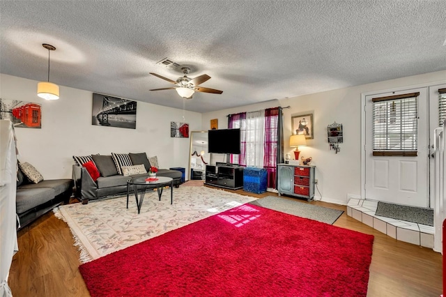 living room featuring ceiling fan, plenty of natural light, hardwood / wood-style floors, and a textured ceiling