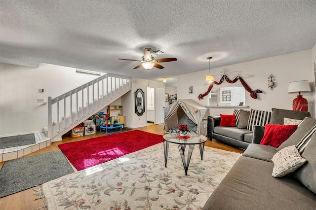 living room with ceiling fan, light hardwood / wood-style flooring, and a textured ceiling