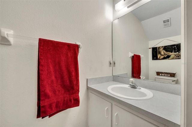 bathroom with vanity, lofted ceiling, and toilet