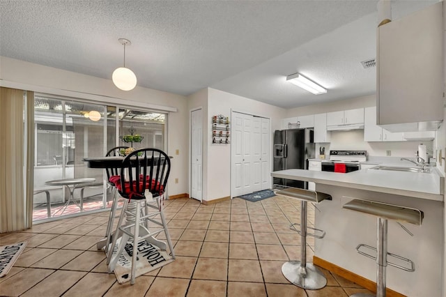 kitchen with black fridge with ice dispenser, sink, electric stove, white cabinetry, and hanging light fixtures