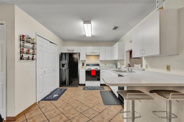 kitchen featuring a kitchen breakfast bar, black fridge, sink, white range with electric stovetop, and white cabinetry