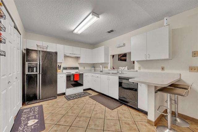 kitchen with black appliances, a kitchen bar, white cabinetry, and kitchen peninsula