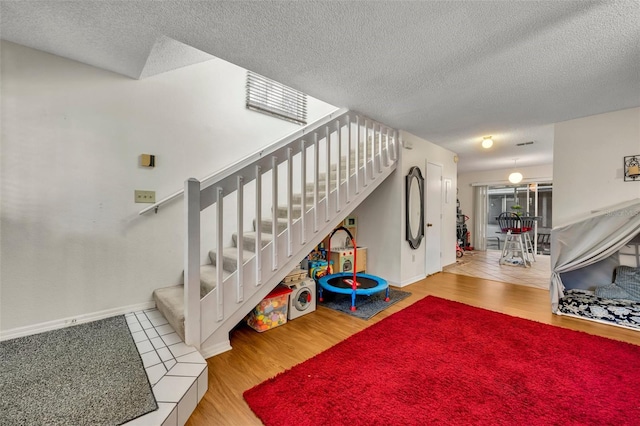 stairs featuring a textured ceiling and hardwood / wood-style flooring