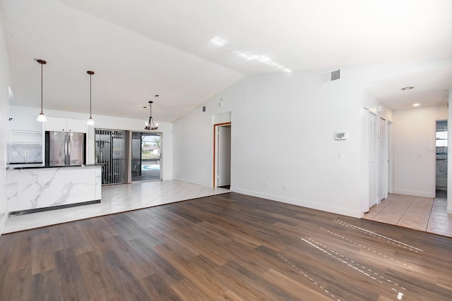 unfurnished living room featuring vaulted ceiling and light hardwood / wood-style flooring