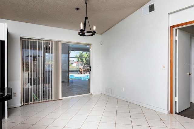 unfurnished dining area with light tile patterned flooring, a textured ceiling, and an inviting chandelier